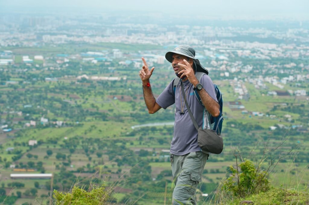 Man in Gray Shirt and Gray Pants Wearing Black Backpack Standing on Top of Mountain during